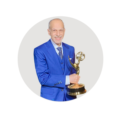 Tom Ohanian holding an Emmy Award while wearing a blue suit from SamSurin